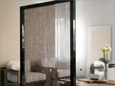 Black chain link curtain as screen to decorate the room, and there are two sofas, one table in it.