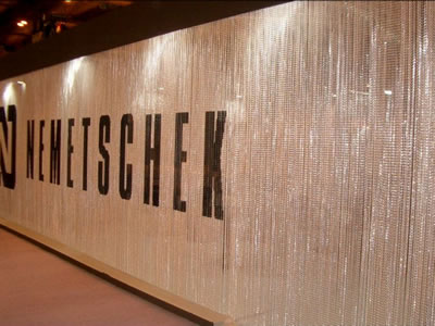Huge chain link screen as wall curtain is printed with several black letters.