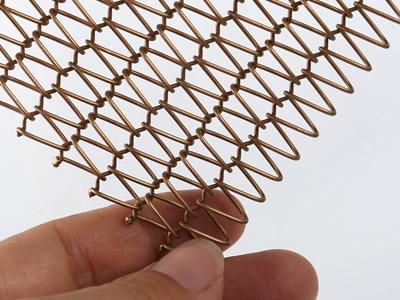 A piece of copper fine round wire mesh belt is held by one's hand.