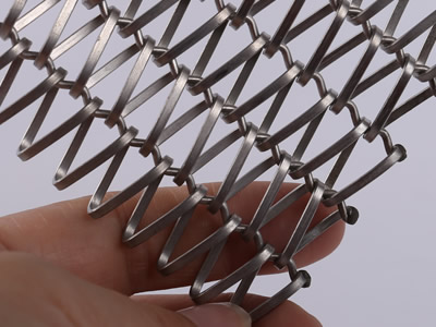 A piece of flat wire mesh belt with bend rod in metallic color is held in one's hand.