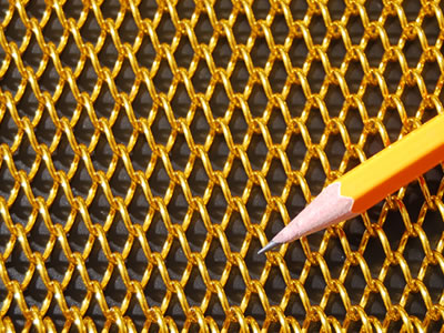 Detailed picture about golden metal coil curtain on the black background, and a yellow pencil on it for contrast.