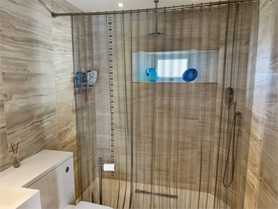 Stainless steel metal coil drapery used as a bathroom curtain