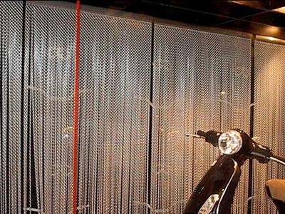 Chain link curtain as background for a motorcycle and its tire.