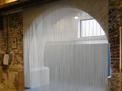 Chain link curtain decorates arched door of the shower room, and there is a mop beside it.