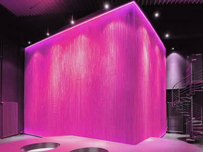 Metal bead curtain forms a space and become shinning dark pink under the lamp lights.