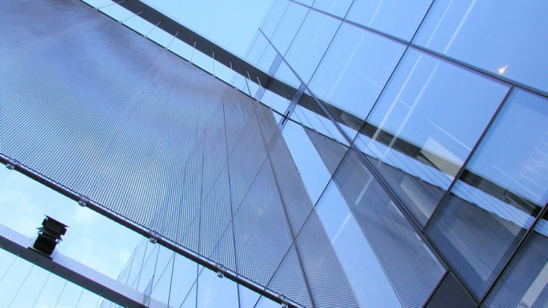 Huge metal coil screens is hanging suspended in mid-air between the buildings.