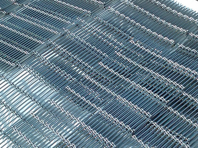 Pieces of woven wire curtain in metallic color is lying on the plastic film outside.