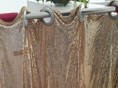 Golden scale mesh curtain fixed on the circular ring is hanging on the stainless steel rod.